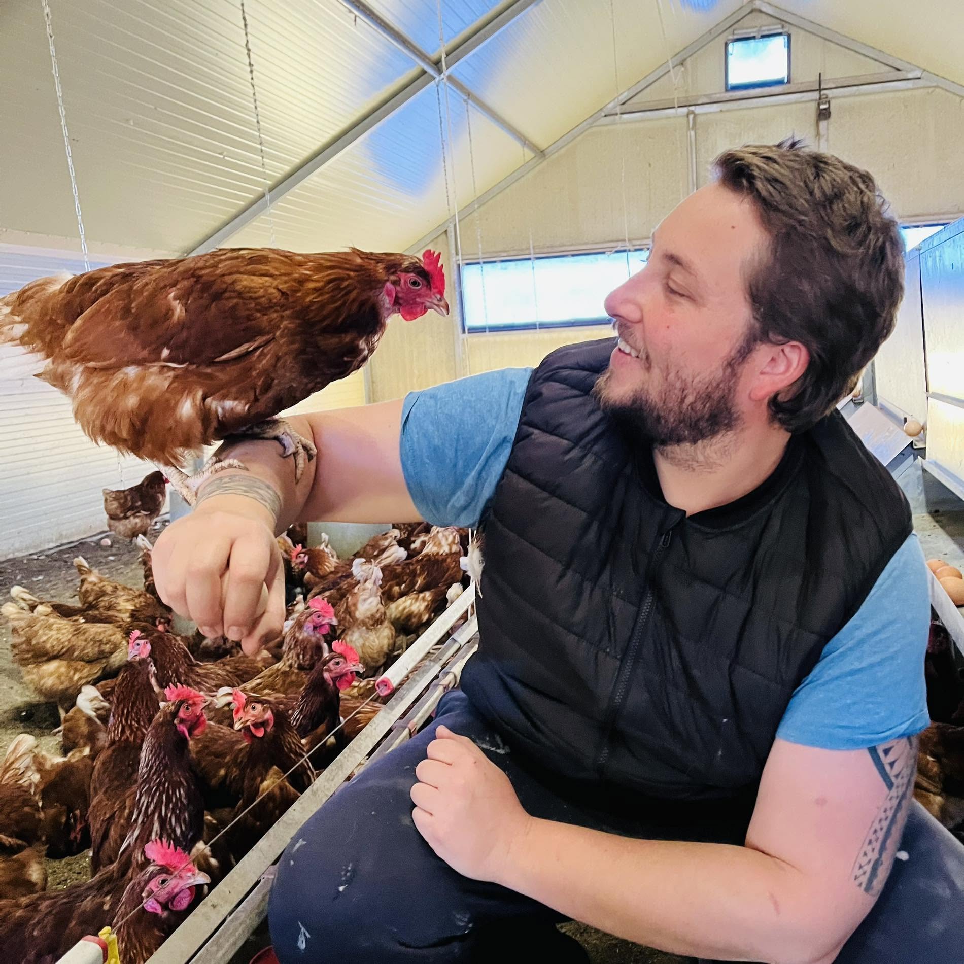 Romain, éleveur, avec une de ses poules pondeuses